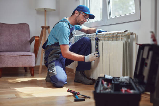 Central heating mechanic and handyman fixing home radiator, gas crisis and seasonal issues. stock photo