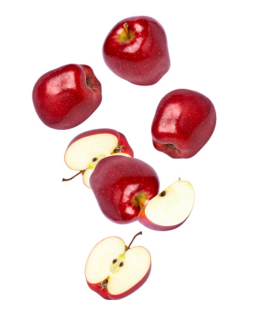 Red washington apples with cut half slice flying in the air isolated on white background.