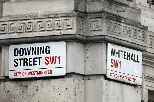 Photo of Downing Street and Whitehall signs on the corner where both streets meet in London, UK.