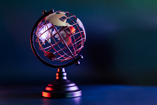Modelo metálico de un globo terráqueo con mapa en luz de neón azul y rojo. Bipolaridad del mundo. Concepto de geografía. Enfoque selectivo, Espacio de copia. photo