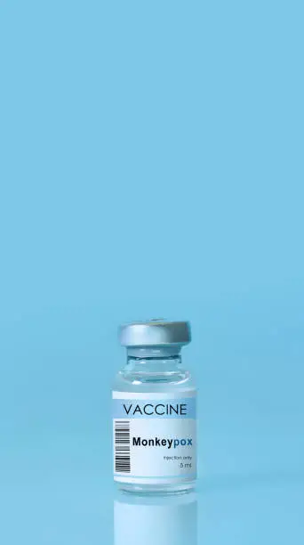 Photo of Vial with vaccine Monkeypox on a blue background.The concept of medicine, healthcare and science.Monkeypox is a viral zoonotic disease. Monkeys may harbor the virus and infect people.