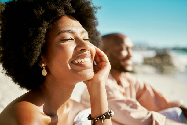 Beauty, skincare and face of a beautiful woman glowing under the natural sunlight at the beach. Stunning afro girl smiling looking confident and happy with her soft, shining and flawless skin outdoor stock photo