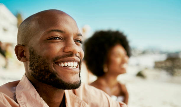 istock Happy, confident and smiling black man enjoying a beach view while on holiday or vacation with his girlfriend. Handsome and relaxed african american male and his wife on a weekend getaway by the sea 1414026352