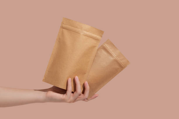 istock Woman's hands hold cardboard packages for tea or snacks on a beige background. Tea branding and packaging mockup. 1414026862