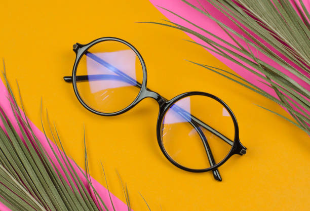 istock Stylish round glasses on a colored background with palm leaves 1414027946