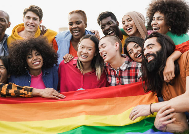 group of happy diverse people having fun outdoor with lgbt rianbow flag - focus on bald girl - gay pride flag gay pride gay man homosexual imagens e fotografias de stock