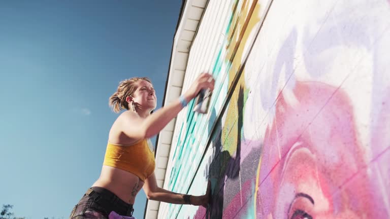 Female artist painting large wall mural