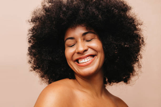 donna attraente con i capelli afro che sorride felicemente in uno studio - capelli neri foto e immagini stock