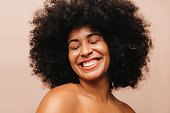 Attractive woman with Afro hair smiling happily in a studio