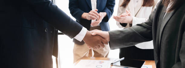 istock Two  business men shaking hands while their colleagues applauding in the background 1414034491