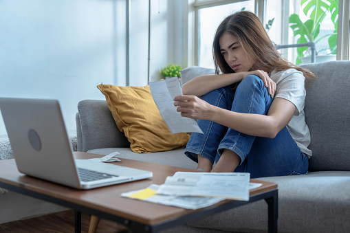 Young Asian woman stressed when she saw the expenses on her bill, Financial problems, Indebtedness, Lose a job.