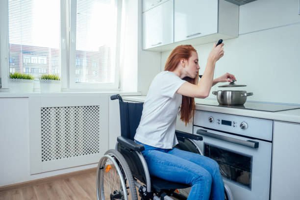disabled redhaired ginger woman in wheelchair preparing meal in kitchen stock photo
