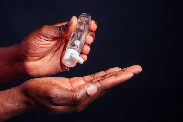 close up hands of afro male useing antiseptic in studio black background.intimate masturbation lubricant stock photo