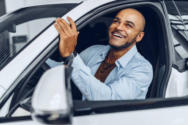 ritratto di un bell'uomo afroamericano felice seduto nella sua auto appena acquistata - car african descent shopping car dealership foto e immagini stock