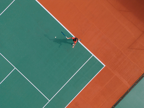 Drone point of view Asian Indian Female Tennis Player Serving The Ball practicing at tennis court directly above