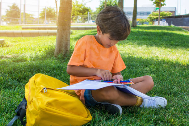 istock Preschooler doing homework in the schoolyard, sitting on the grass. 1414038807