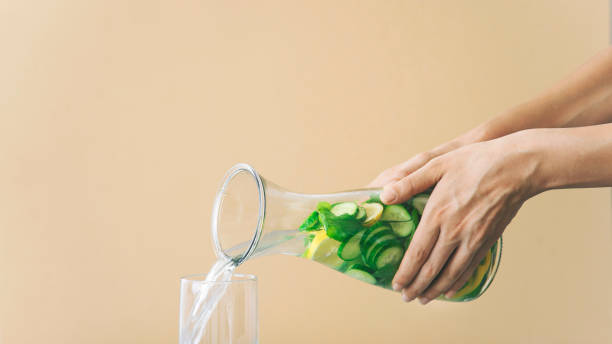 woman hand pours detox water into glass. Detox water, fitness, healthy nutrition diet concept. stock photo