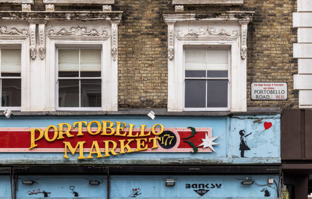 Portobello Road Market and street sign on an old building with Banksy graffiti elements alongside. London, UK - 11 March 2022: Portobello Road Market and street sign on an old building with Banksy graffiti elements alongside. banksy stock pictures, royalty-free photos & images