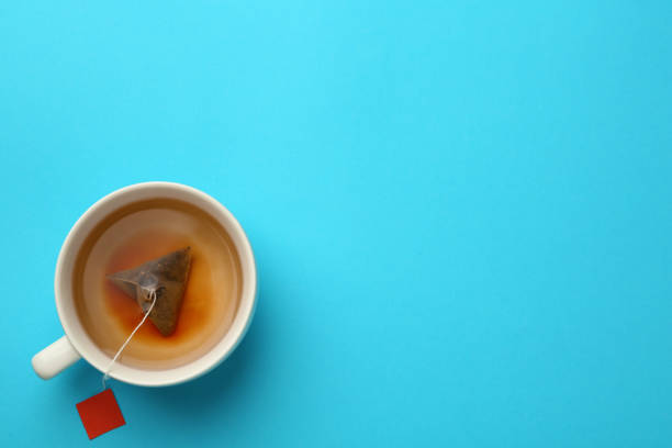 istock Tea bag in cup of hot water on light blue background, top view. Space for text 1414039698