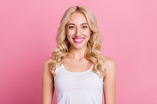 Portrait of attractive cheerful content blond girl wearing white tshirt isolated over pink pastel color background.