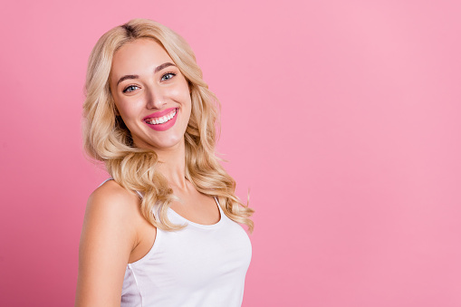 Profile side view portrait of attractive cheerful blond girl copy blank empty space ad isolated over pink pastel color background.