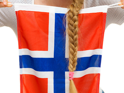 Blonde student girl unrecognizable young woman with long hair braid holding norwegian flag, close up. Education and travel.