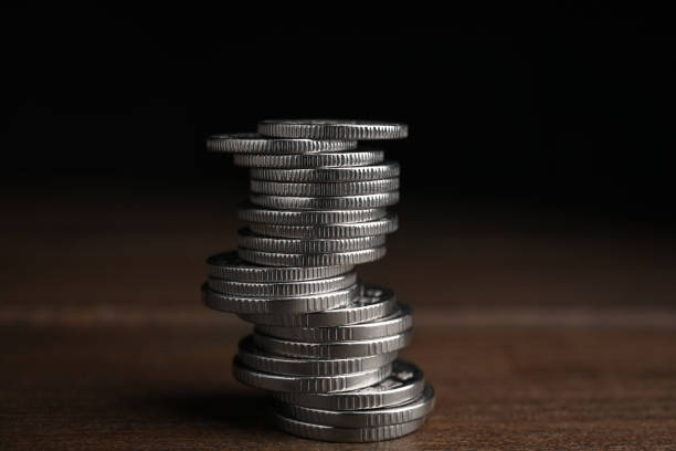 istock Many coins stacked on wooden table against black background 1414042435