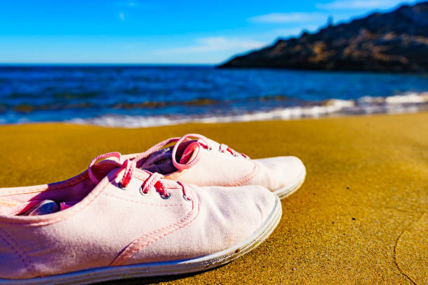 istock Female sneakers on sand beach 1414042492