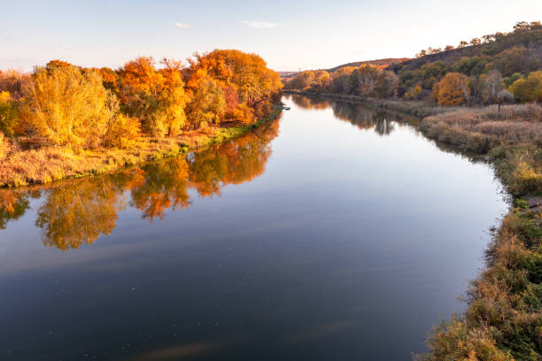 istock Multicolored autumn trees in the sun on the river bank 1414044336