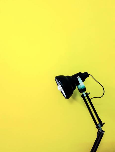 Black desk lamp on yellow empty background