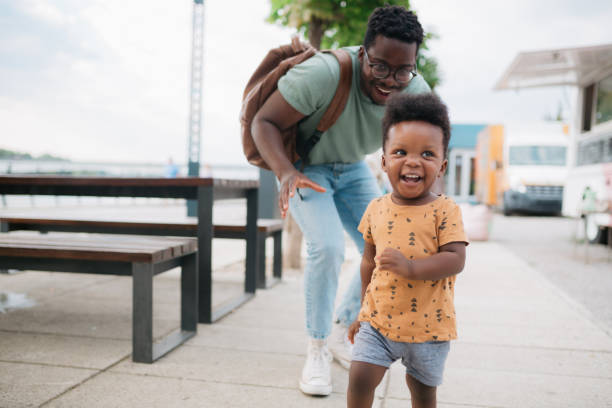 istock Little boy taking his first steps with the help of his father 1414045597