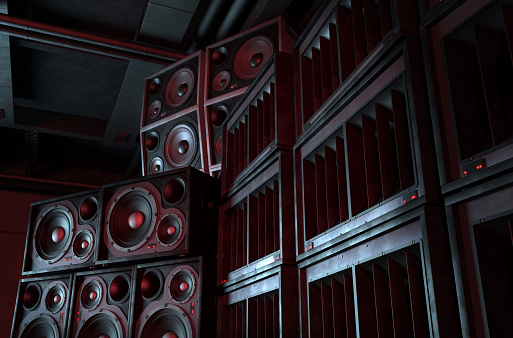 Loudspeakers and subwoofers stacked on each other illuminated by blue and red lights on a dark background. Powerful sound system with modern audio equipment for an underground music club where punk and rock music is played. Digitally generated image. Copy space.