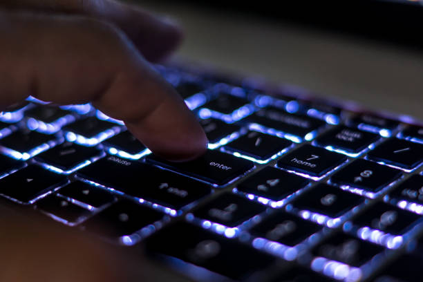 istock Finger pressing Enter key close up on backlit keyboard.  Computer keyboard, laptop keyboard. 1414047441