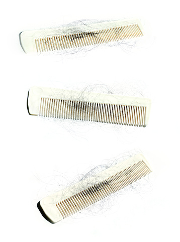 Close up comb and fallen hairs over white background