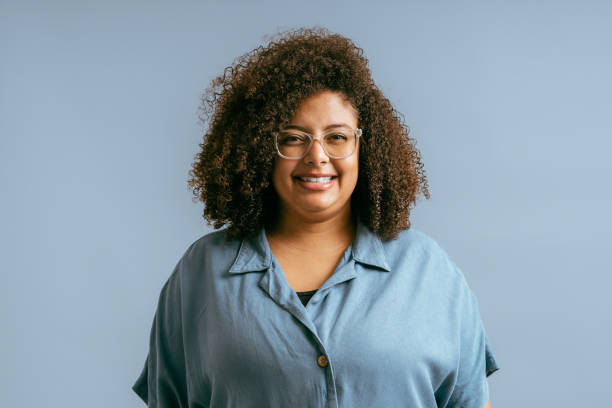 portrait of young woman with curly hair in studio - plussize model fotos stockfoto's en -beelden