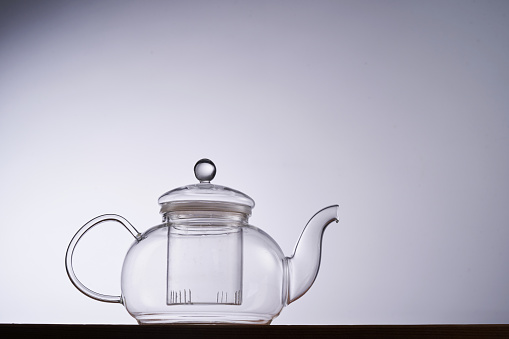 Turkish transparent glass tea cup and teapot with tea on a white background with reflection
