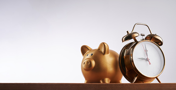 Piggy bank with alarm clock against white background