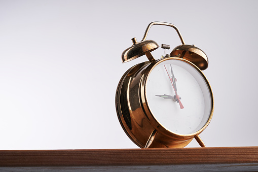 vintage golden color alarm clock against white background