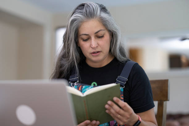 Adult Online Learning A woman in her 40's using a laptop for online learning at home gray hair young woman stock pictures, royalty-free photos & images