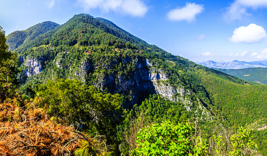 Conical mountain panorama with a green forest and roadside precipices in the Hidalgo incarnation, with a blue sky with clouds