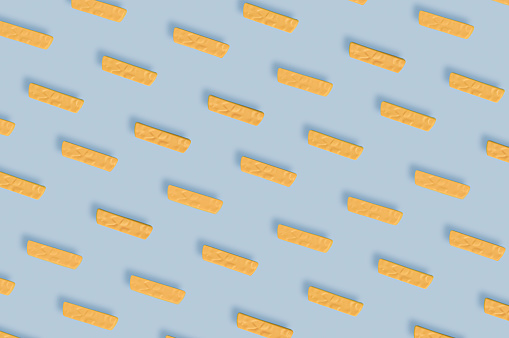 Seamless pattern of plastic childrens toy French fries on blue. Concept of harmful artificial food. Unhealthy. Not organic. Not useful. Examining today's food industry