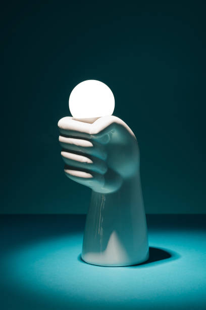 istock Concrete hand holding a light bulb on a dark background. 1414064153