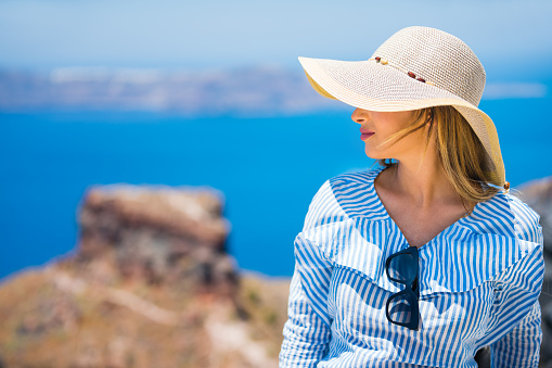 Happy young woman solo traveler enjoying view from village Imerovigli on Santorini island, Greece. Check for my similar photos from same series. Photo taken by Sony a7R II, 42 Mpix.