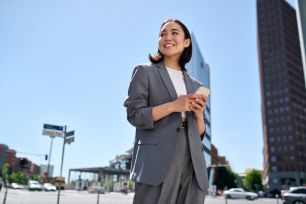 giovane donna d'affari asiatica di successo che usa il telefono in piedi sulla strada della città. - 4694 foto e immagini stock