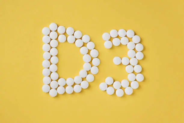 Pills of vitamin D3 on yellow background top view. Concept of vitamin d3. Inscription D3.