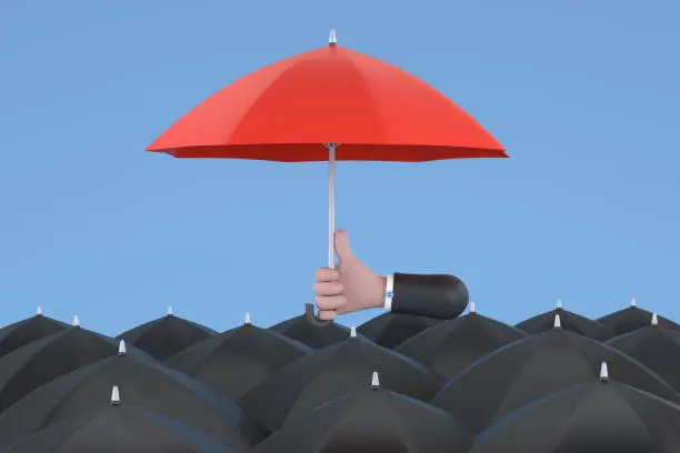 Photo of Uniqueness and individuality. Hand holding a red umbrella among people with black umbrellas.