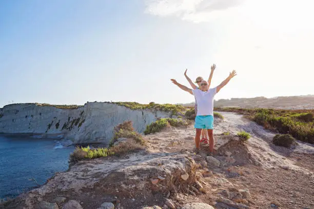 Photo of Middle-aged couple enjoy of travel trip in scenic place with raised hands