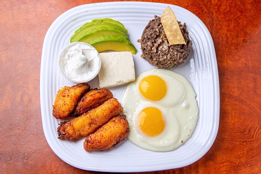 Latin American Breakfast (desayuno latinoamericano) fried plantain (platano maduro) , queso fresco, rice, sliced avocado, and fried eggs