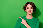 Photo of shiny cute woman wear casual t-shirt pointing finger empty space isolated green color background