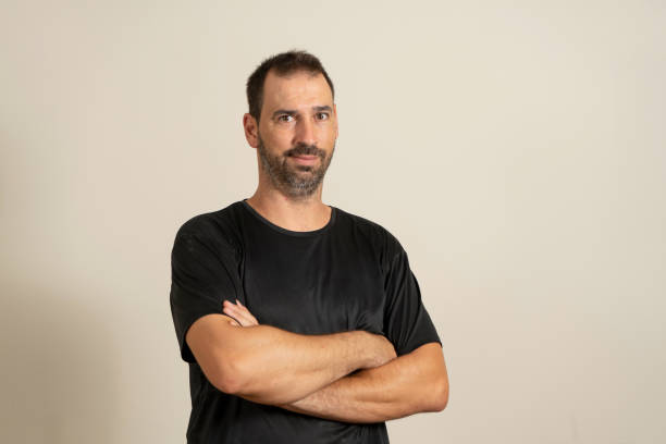 istock Bearded latin man posing funny with crossed arms isolated on beige studio background. 1414074090